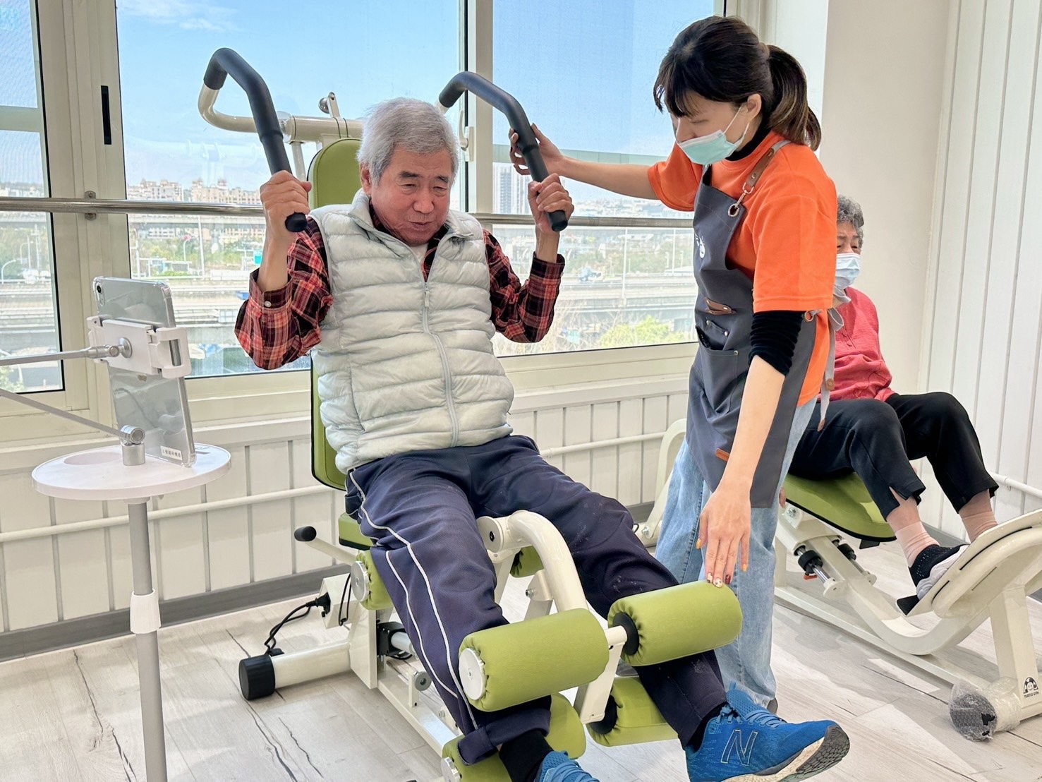 長輩在明亮舒適的場域中使用智慧版等速肌力設備強化下肢肌力